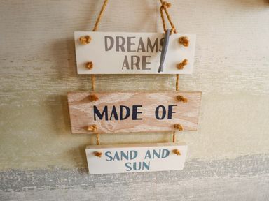 A wooden sign with the text 'DREAMS ARE MADE OF SAND AND SUN' at Moggs Retreat in Chapel St Leonards