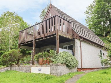 A house with a wooden balcony and garden surrounded by trees at Valley Lodge 52 Callington