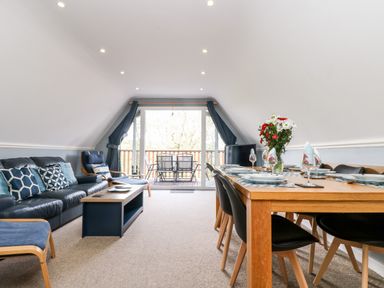 A dining area with a wooden table set for six and a living area with a couch and chairs at Valley Lodge 52 in Callington