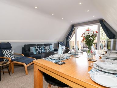 A dining table set with plates glasses and napkins next to a sitting area with chairs and a sofa at Valley Lodge 52 in Callington