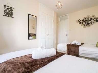 A bedroom with two single beds towels on beds wall mirror and closet at Valley Lodge 52 in Callington