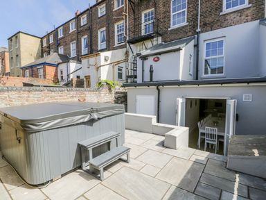 An outdoor patio with a hot tub and steps leading to an indoor dining area at Station House in Scarborough