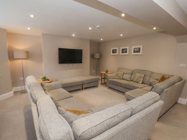 A living room with grey sofas a wall-mounted television and floor lamps at Station House in Scarborough