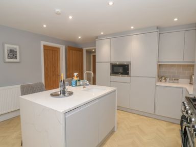 A kitchen with an island countertop sink cabinets a microwave and wooden doors at Station House in Scarborough