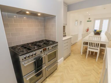 A kitchen with a double oven gas stove and a dining table with white chairs at Station House in Scarborough