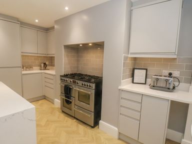 A kitchen with a stainless steel oven gas hob toaster kettle and light grey cabinets at Station House in Scarborough