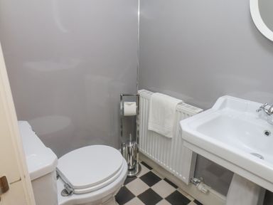A bathroom with a toilet a pedestal sink a towel on a radiator and a free standing toilet paper holder at Station House in Scarborough
