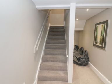 A stairway with carpeted steps and a railing beside a hallway with bean bags and a framed picture on the wall at Station House in Scarborough