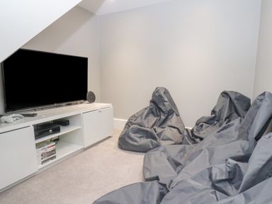 A media room with a flat screen tv on a white cabinet and gray bean bag chairs at Station House in Scarborough
