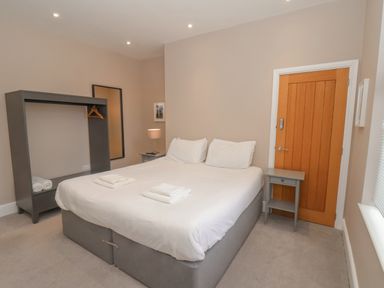 A bedroom with a double bed beside a wooden door and gray furniture at Station House in Scarborough