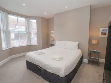 A bedroom with a double bed two bedside tables with lamps and a large window at Station House in Scarborough