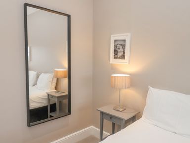 A bedroom corner with a bedside table lamp a framed picture and a wall mirror at Station House in Scarborough