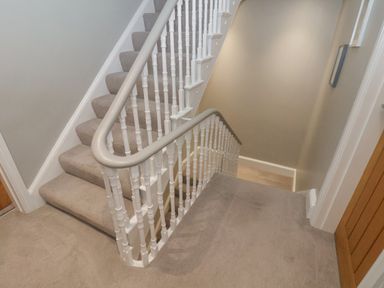 A carpeted staircase with white banisters and beige walls at Station House in Scarborough