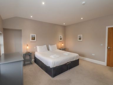A bedroom with a double bed two bedside tables with lamps a dresser and three framed pictures at Station House in Scarborough
