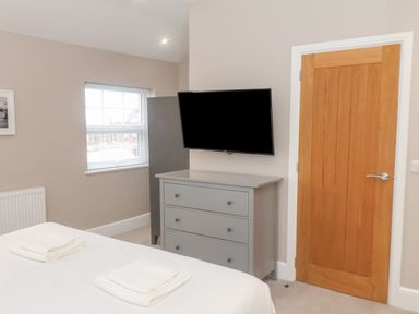 A bedroom with a gray chest of drawers and a TV mounted above it at Station House in Scarborough