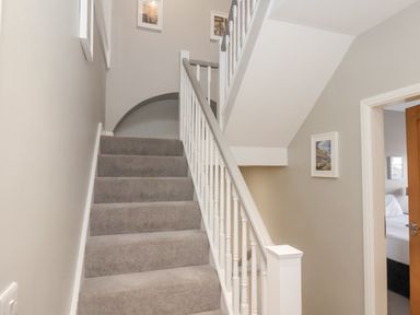 A carpeted staircase with white banisters and framed pictures on the walls at Station House in Scarborough