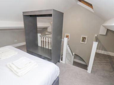 A bedroom with a gray cabinet next to a staircase with white railings at Station House in Scarborough