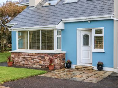The exterior of a blue house with a white door stone wall base and potted plants at The Blue Annex The Spa near Tralee County Kerry