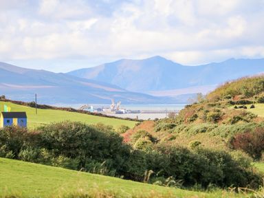 A green countryside landscape with a small blue and yellow shed and mountains in the background at The Blue Annex in The Spa near Tralee County Kerry