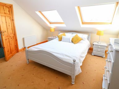 A bedroom with a bed white bedding two yellow pillows two bedside tables with lamps and skylights at The Blue Annex The Spa near Tralee County Kerry