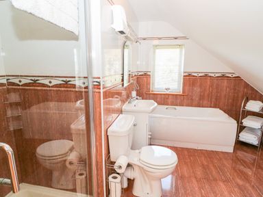 A bathroom with a shower, toilet, sink, bathtub, window, and towel rack at The Blue Annex in The Spa near Tralee County Kerry