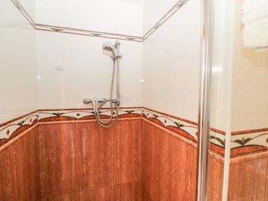 A shower area with a handheld showerhead and decorative tiles at The Blue Annex in The Spa near Tralee County Kerry