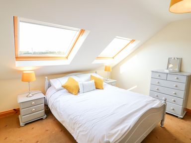 A bedroom with a bed with yellow pillows two bedside tables with lamps and a chest of drawers at The Blue Annex The Spa near Tralee County Kerry