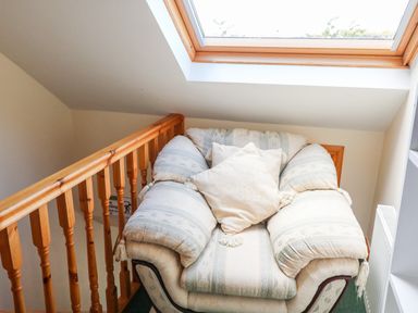 A cushioned armchair with pillow next to wooden railing and skylight window at The Blue Annex The Spa near Tralee County Kerry