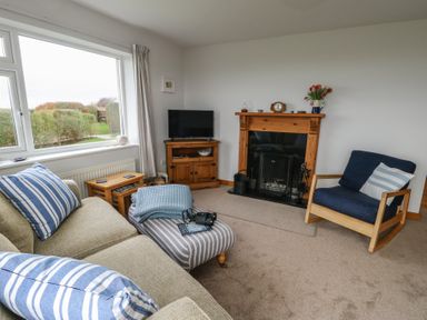 A living room with a sofa and television at Yr Orsedd in Llanfaethlu
