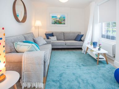 A living room with two gray sofas blue rug and a white coffee table at Bryn Teg Cottage in Menai Bridge