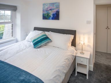 A bedroom with a bed headboard bedside table and a window at Bryn Teg Cottage in Menai Bridge