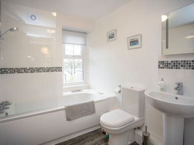 A bathroom with a bathtub shower toilet sink and window at Bryn Teg Cottage in Menai Bridge