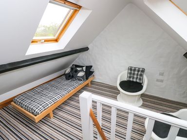 An attic room with a single bed and two chairs with cushions at The Old Stables in Fishguard