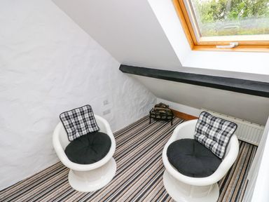 A small room with two white chairs with cushions near a window at The Old Stables in Fishguard