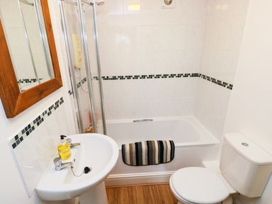 A bathroom with a sink a toilet a bathtub and a mirror at The Old Stables in Fishguard
