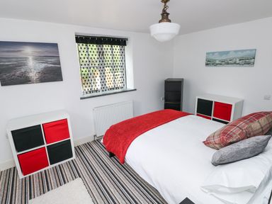A bedroom with a bed a window and storage units with red and black drawers at The Old Stables in Fishguard