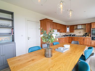 A kitchen with a wooden dining table and blue and gray chairs at Seacoast Cottage in Castlerock