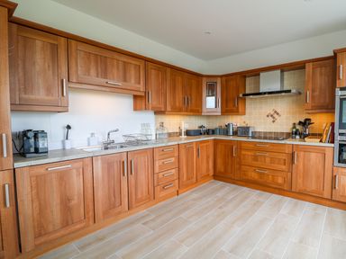A kitchen with wooden cabinets a sink coffee maker toaster and various kitchen utensils at Seacoast Cottage in Castlerock