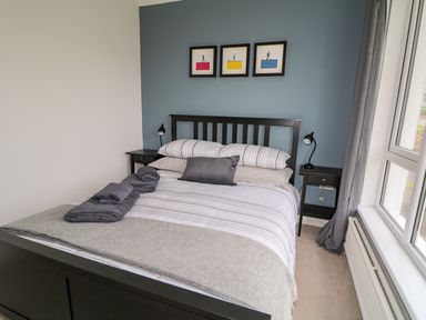 A bedroom with a bed with striped bedding and folded towels on top at Seacoast Cottage in Castlerock