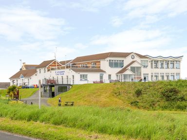 A golf club building with a sign reading Castlerock Golf Club on a grassy hill in Castlerock