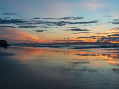 A beach with waves and a sunset reflecting on the water at Seacoast Cottage in Castlerock