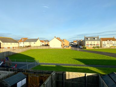 A grassy open area with a playground and surrounding houses at 39 Longbeach Drive in Beadnell