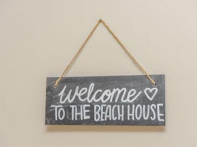 A hanging sign with welcome to the beach house text on a beige wall at 39 Longbeach Drive in Beadnell