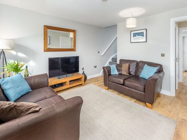 A living room with two brown leather sofas a television and a wooden mirror at 39 Longbeach Drive in Beadnell