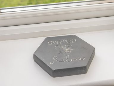 A hexagonal stone plaque with the words switch off and relax on a windowsill at 39 Longbeach Drive in Beadnell