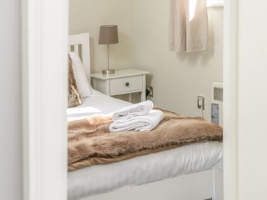 A bedroom with a bed covered with a brown throw and folded white towels on it a bedside table with a lamp at 39 Longbeach Drive in Beadnell
