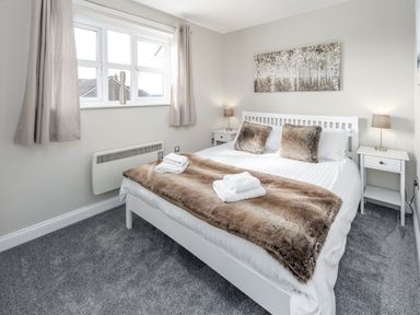 A bedroom with a double bed two side tables lamps and a window at 39 Longbeach Drive Beadnell