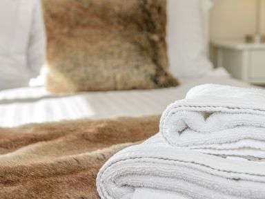 A bed with white towels folded on top and a brown cushion at 39 Longbeach Drive in Beadnell
