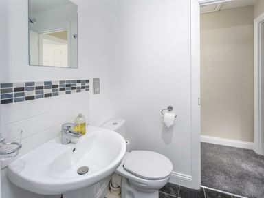A bathroom with a sink mirror toilet and tiled floor at 39 Longbeach Drive in Beadnell