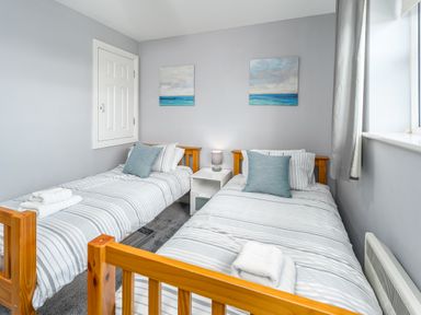 A bedroom with two single beds striped bedding cushions and a window at 39 Longbeach Drive Beadnell